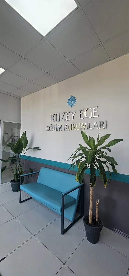 Yeşilova Kuzey Ege Sosyal Etkinlik ve Gelişim Merkezinin turkuaz oturma alanı ve pusula logolu karşılama bölümü